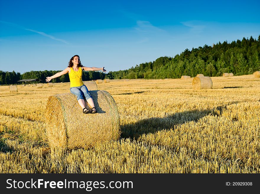 Young girl on a haystack in a field. Russia, Moscow region