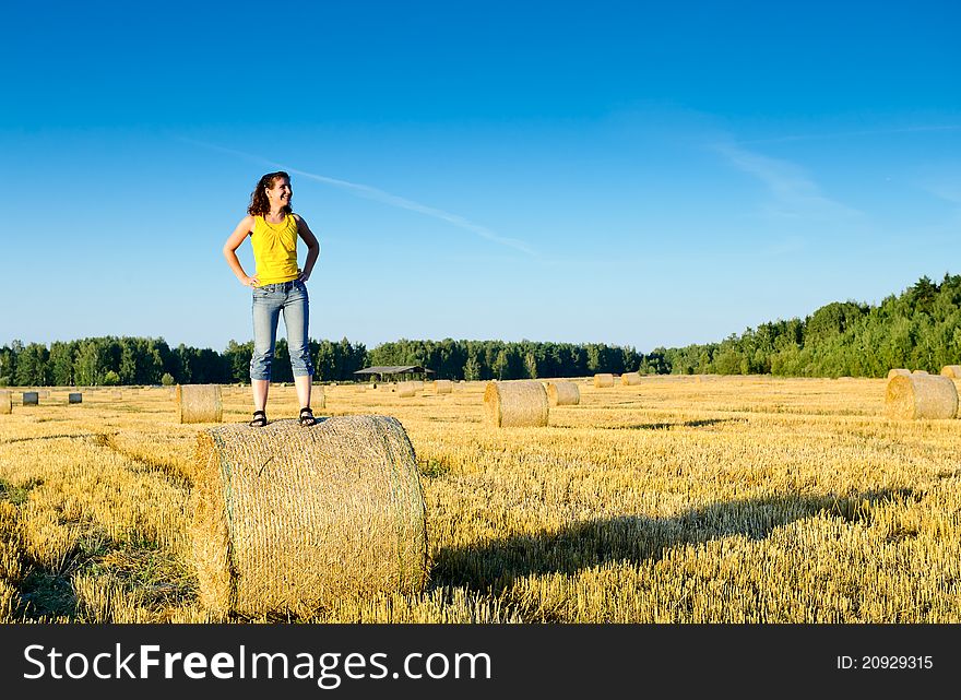 Young girl on a haystack in a field. Russia, Moscow region