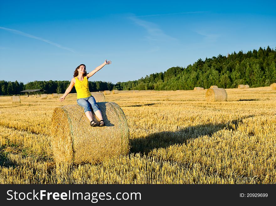 Young girl on a haystack in a field