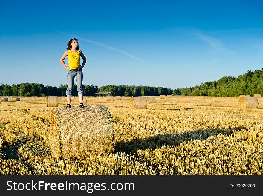 Young girl on a haystack in a field