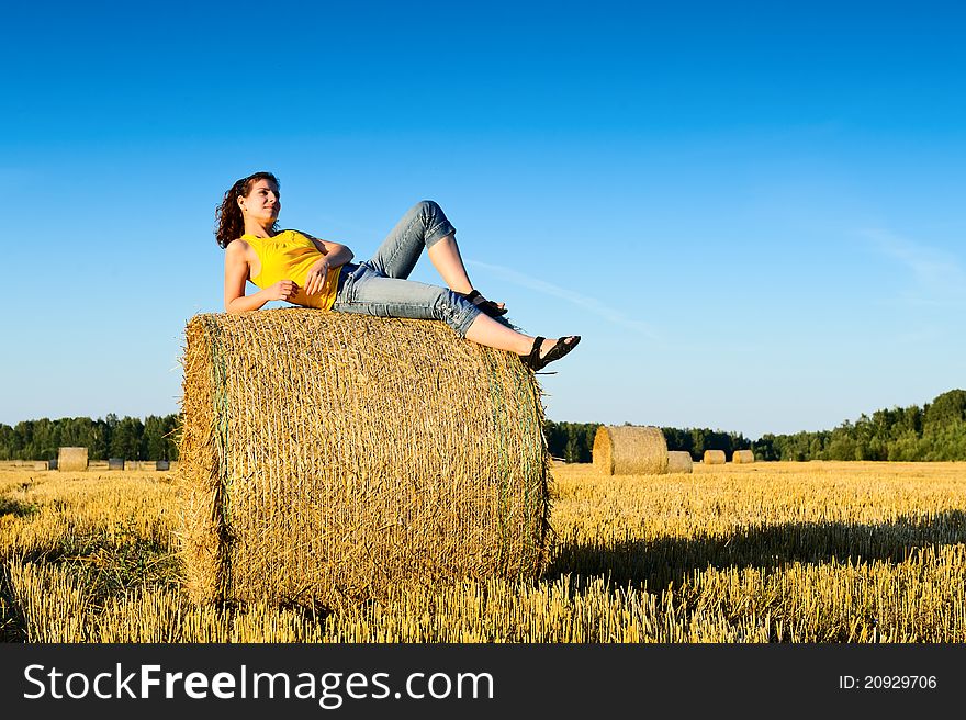 Young girl on a haystack in a field