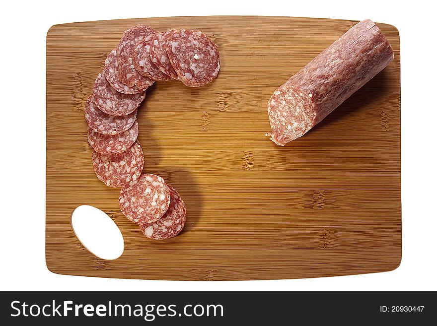 Sliced salami laying next to a knife on a brown cutting board. Sliced salami laying next to a knife on a brown cutting board.