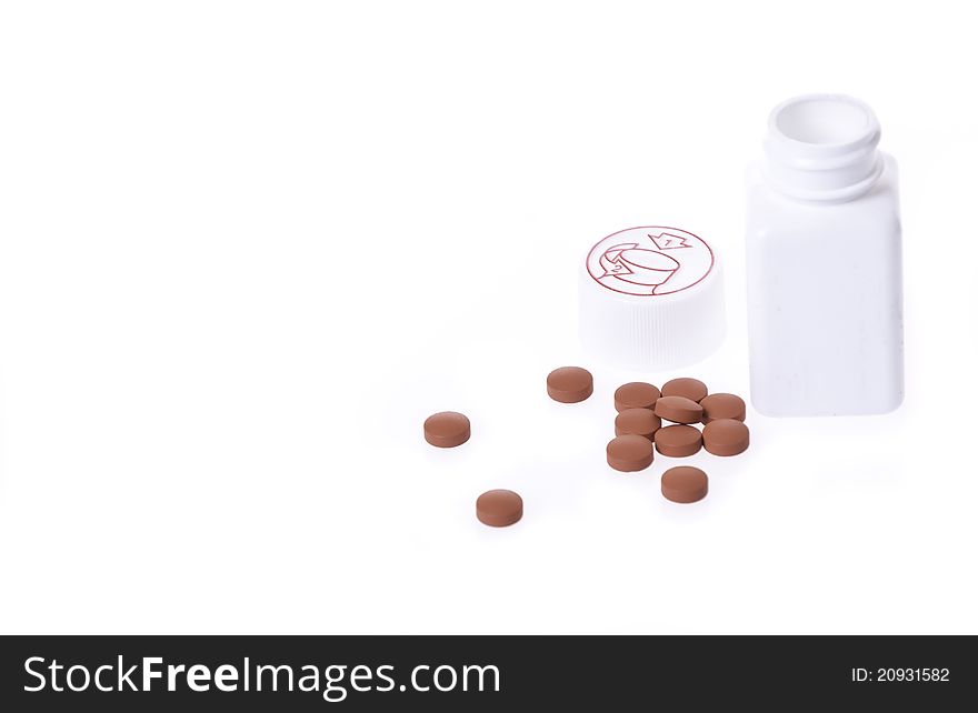 A white pill bottle with red generic pills on a white background next to child safety cap. A white pill bottle with red generic pills on a white background next to child safety cap.