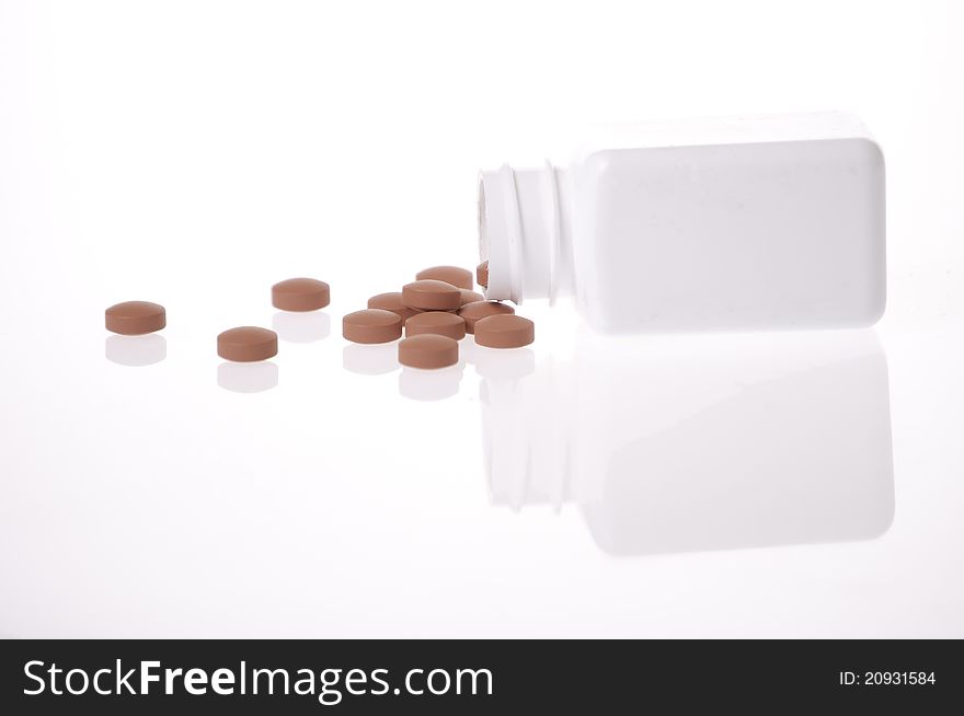 A white pill bottle with red generic pills on a white background. A white pill bottle with red generic pills on a white background.