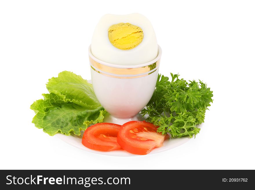 Hard-boiled egg with a slice of tomato, leaf lettuce and parsley, isolated on a white background