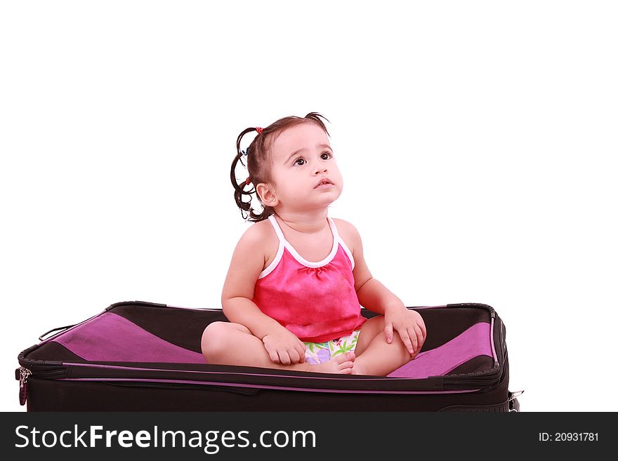 Cute little girl sitting on the black suitcase.