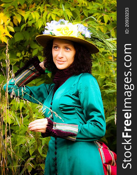 A beautiful woman in a green vintage dress and yellow hat