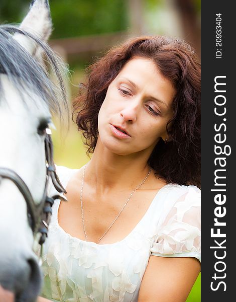 Beautiful woman in white with a horse in the park