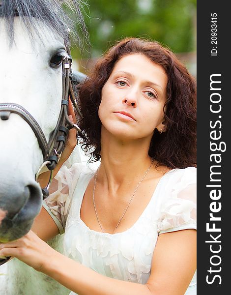 Beautiful woman in white with a horse in the park