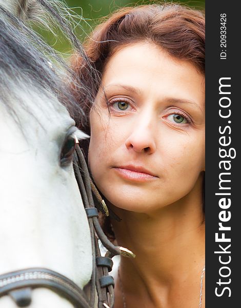 Beautiful woman in white with a horse in the park