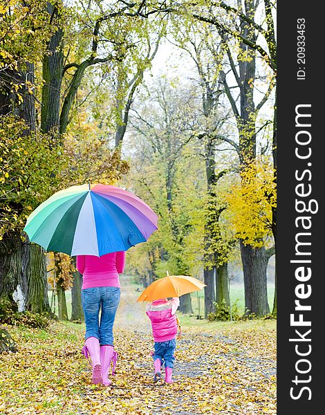 Mother and her daughter with umbrellas in autumnal alley. Mother and her daughter with umbrellas in autumnal alley