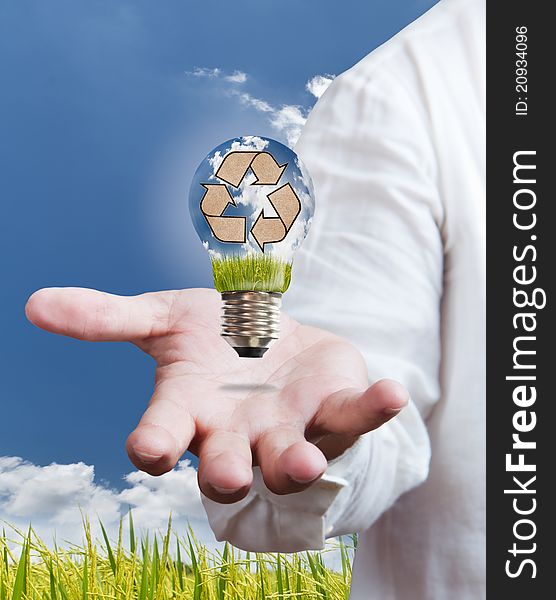 Hand hold a recycle sign inside a light bulb with blue sky background for world saving concept. Hand hold a recycle sign inside a light bulb with blue sky background for world saving concept.