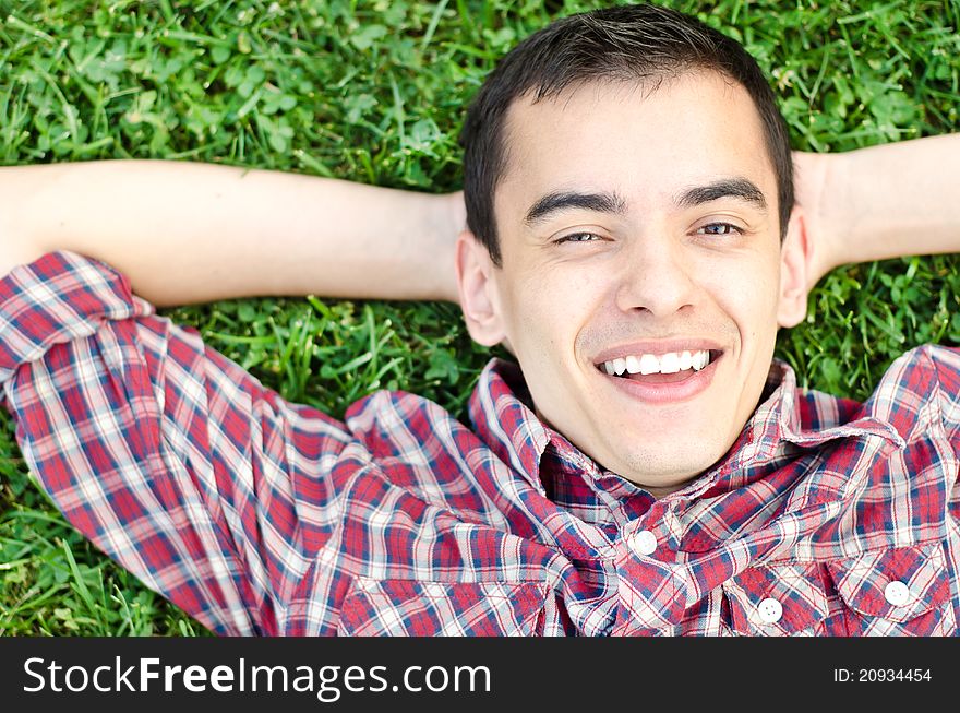 Young handsome man relaxing on the grass smiling