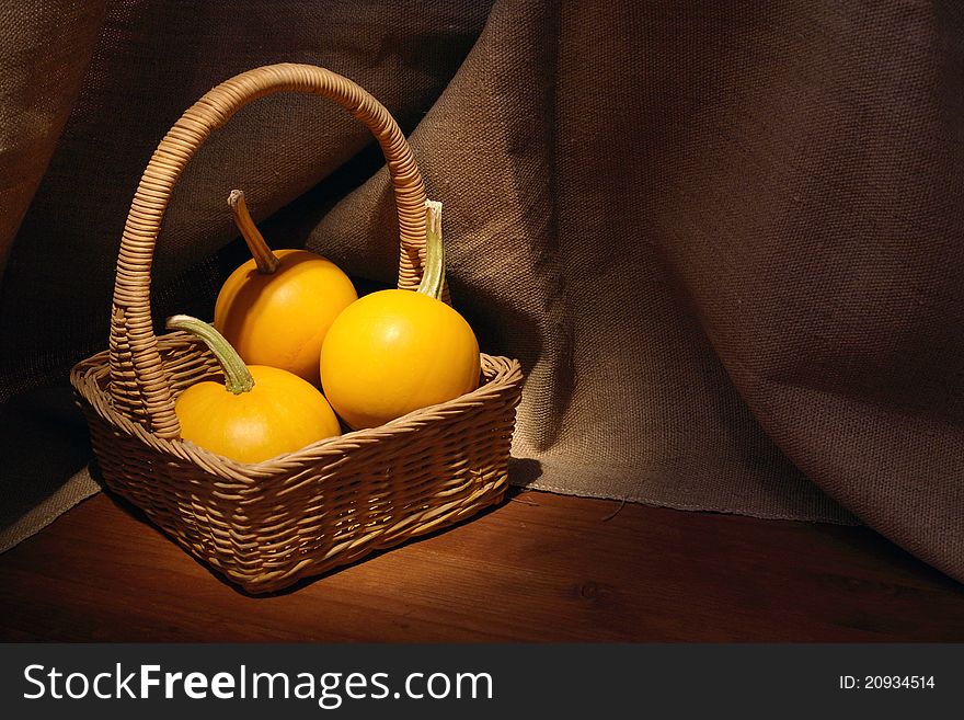 Woven basket with three pumpkins on dark canvas background. Woven basket with three pumpkins on dark canvas background