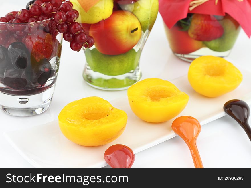 Canned peaches with various fruits on background