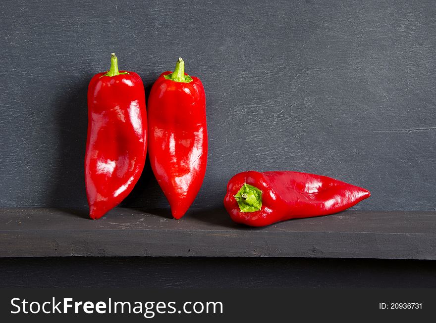 Three red peppers on black background
