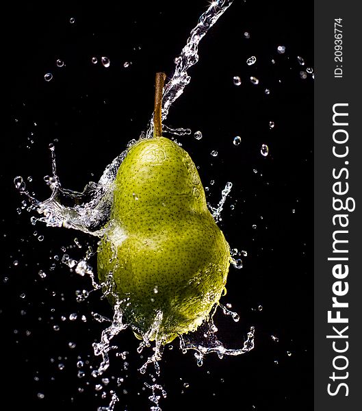 Pear suspended in air splashed with water, isolated on a black background. Pear suspended in air splashed with water, isolated on a black background.