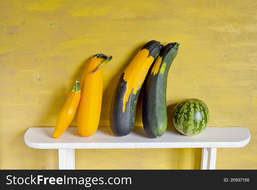 Still-life with courgette and watermelon on yellow background