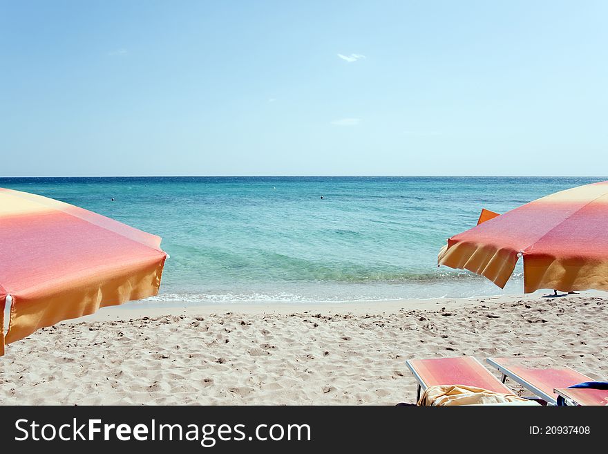 Two Chairs And Two Umbrellas On The Beach