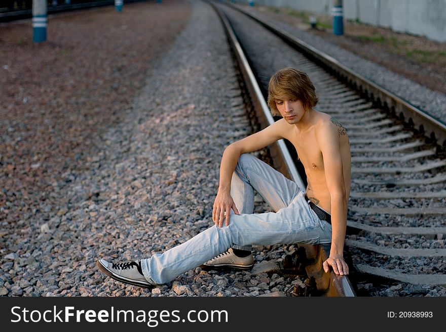 Handsome man walking near rails in summer