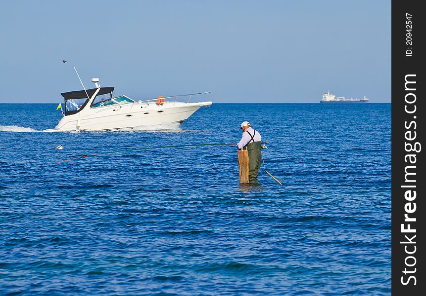 An elderly man fishes in the sea. An elderly man fishes in the sea