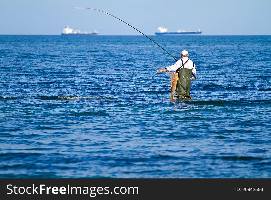 An elderly man fishes in the sea. An elderly man fishes in the sea
