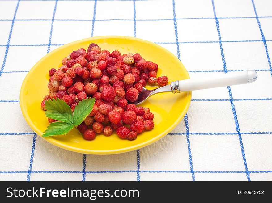 Strawberries on a yellow  plate with green leaf and spoon. Strawberries on a yellow  plate with green leaf and spoon