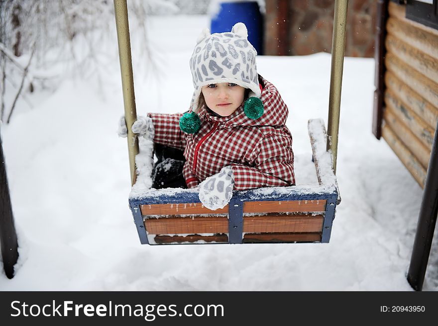 Adorable child girl in red winter coat has fun on seesaw. Adorable child girl in red winter coat has fun on seesaw