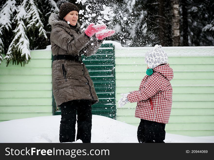 Young mother and her adorable daughter play snowball on a bright winter day. Young mother and her adorable daughter play snowball on a bright winter day