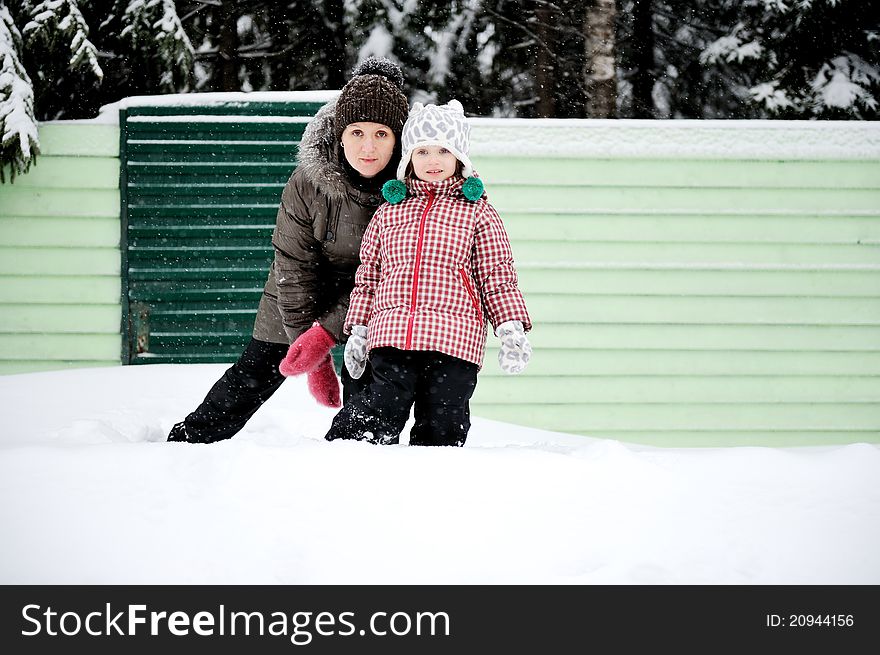 Portrait of young mother and her adorable daughter in the snow on a bright winter day. Portrait of young mother and her adorable daughter in the snow on a bright winter day