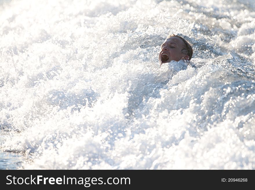 Teenager screams with only head visible over foamy wave. Teenager screams with only head visible over foamy wave