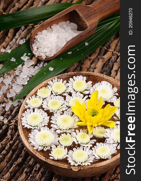 Spa set with sea salt and flowers on the wooden background
