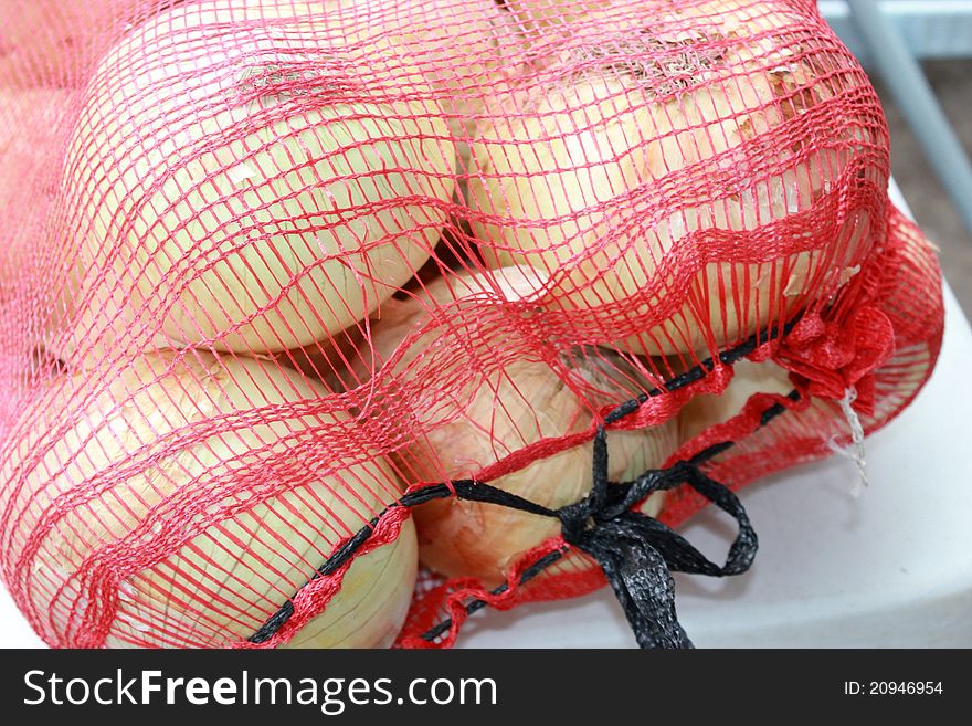A mesh bag of fresh, raw, jumbo onions. A mesh bag of fresh, raw, jumbo onions