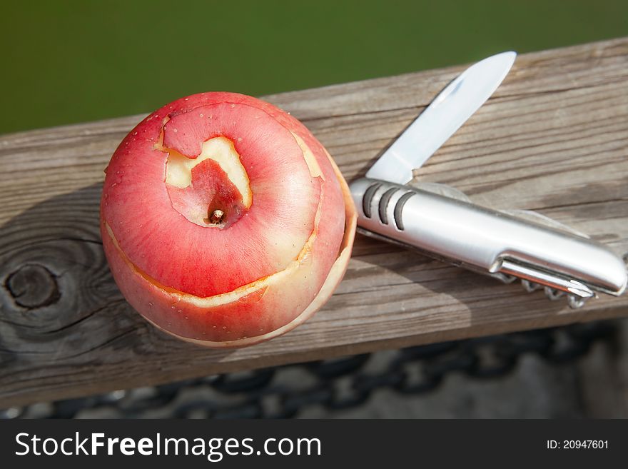 Red peeled apple and knife on wood background. Red peeled apple and knife on wood background