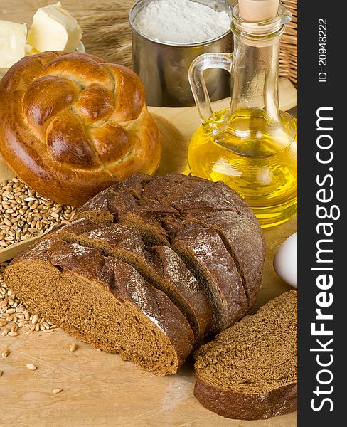 Bakery products and grain on wood background