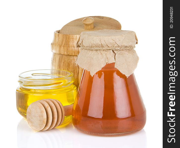 Glass jar full of honey and stick on white background
