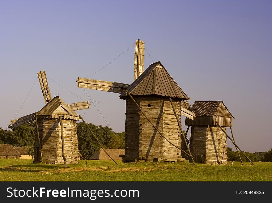 Three old wooden mill on a blue background. Three old wooden mill on a blue background