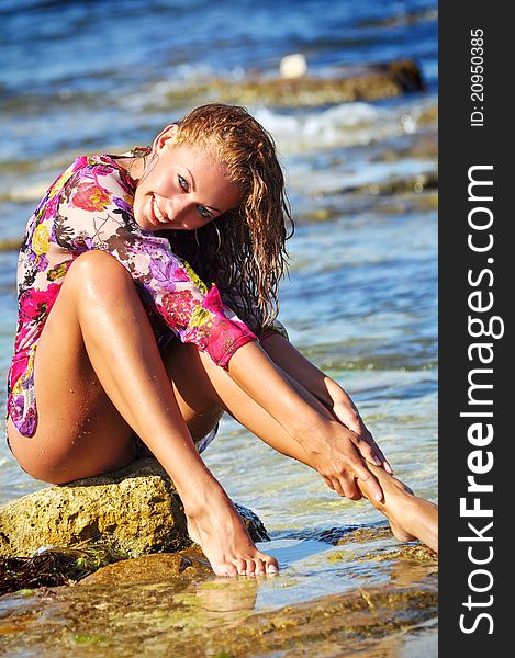 The beautiful young woman on a beach in a wet dres