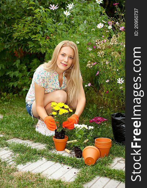Lovely young woman planting flowers in the garden. Lovely young woman planting flowers in the garden