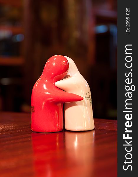 Figures of two saltcellars hugging each other in a candle-light.