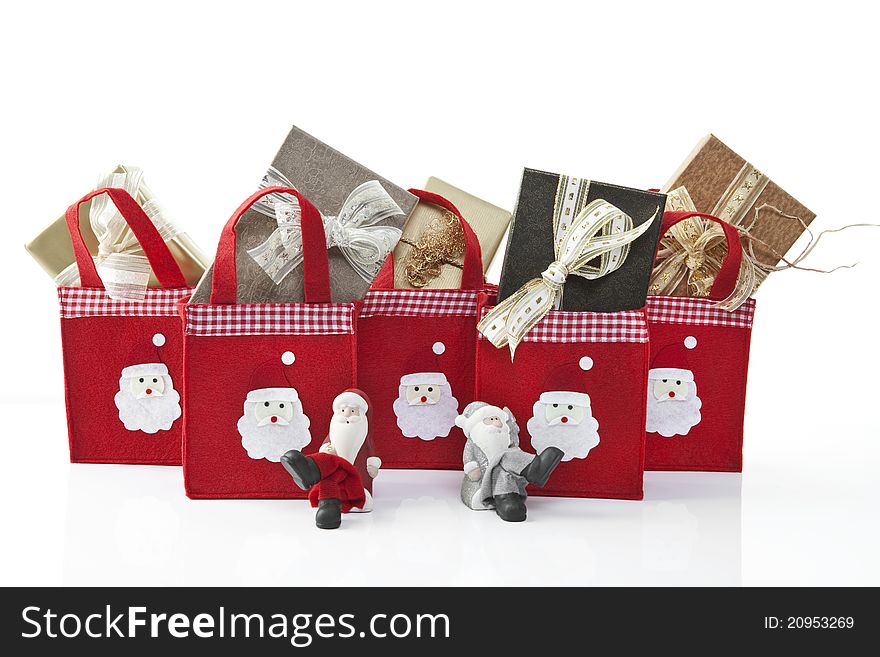 Two Santa Clause figurines sitting in front of christmas parcels