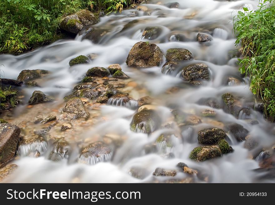 Long exposure image of mountain river falling and flowing trough stone