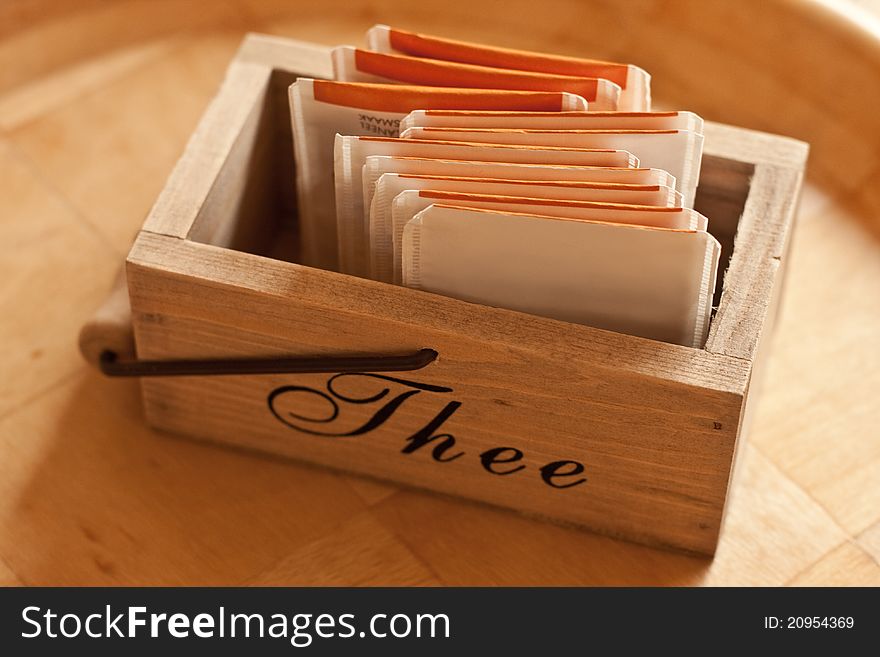 Close-up of a wooden tea box with teabags in it on a wooden tray.