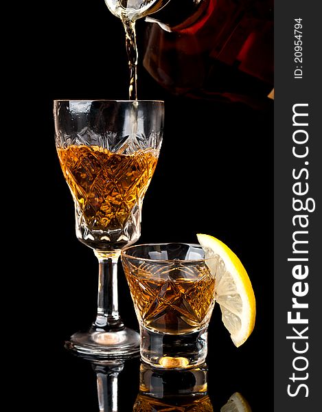 Glass of cognac with lemon isolated on a black background