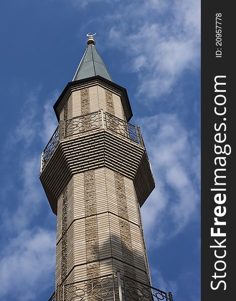 Single minaret against blue sky with clouds