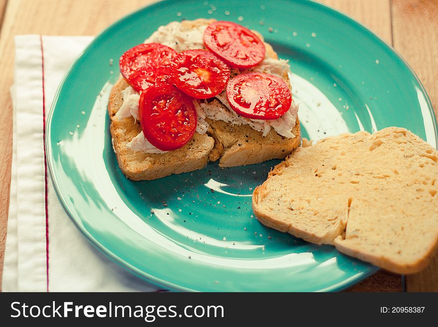 A fresh roasted turkey sandwich with garden fresh tomatoes and homemade sweet potato bread rests open face on a blue plate. A fresh roasted turkey sandwich with garden fresh tomatoes and homemade sweet potato bread rests open face on a blue plate.