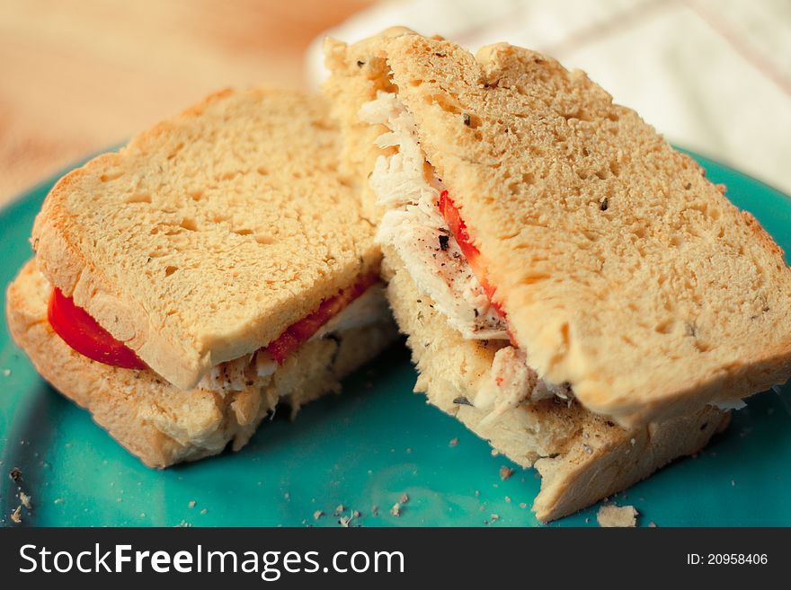 A fresh roasted turkey sandwich with garden fresh tomatoes and homemade sweet potato bread rests on a blue plate. A fresh roasted turkey sandwich with garden fresh tomatoes and homemade sweet potato bread rests on a blue plate.