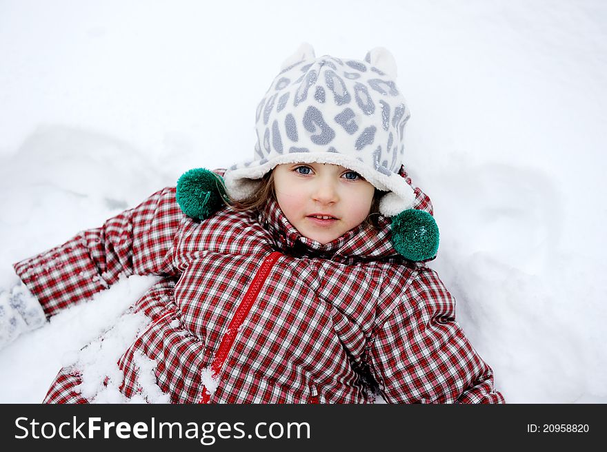 Winter portrait of adorable child girl in warm clothes lying in the snow. Winter portrait of adorable child girl in warm clothes lying in the snow