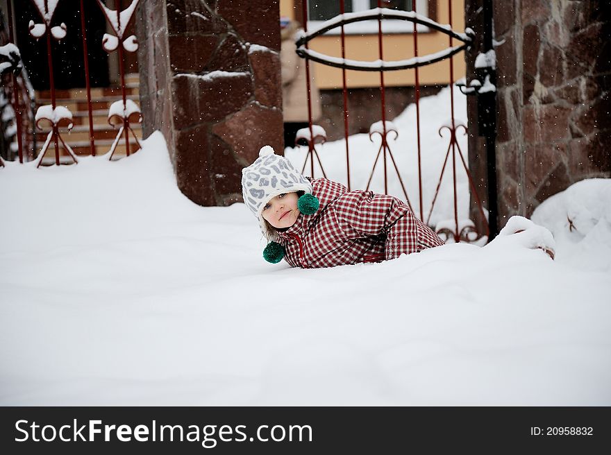 Adorable happy child girl in warm clothes is lying in the snow. Adorable happy child girl in warm clothes is lying in the snow