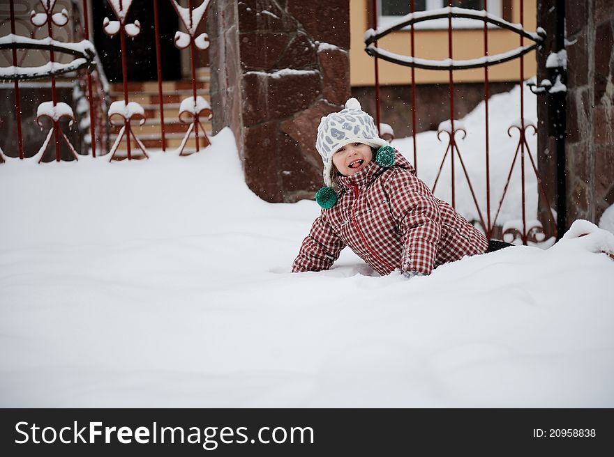 Adorable happy child girl in warm clothes is lying in the snow. Adorable happy child girl in warm clothes is lying in the snow